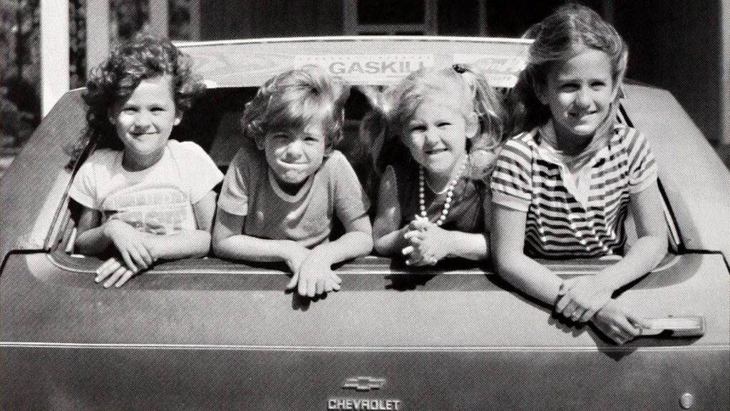 Four children look on from the back window of a Chevrolet station wagon. Coastwatch Magazine. 1979.