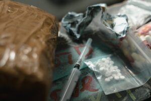 A dramatic scene depicting drugs and syringes on a dark surface, highlighting substance abuse risks.