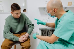 A teenager consults a doctor in a clinic, discussing health concerns.