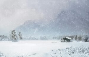 Serene winter landscape featuring a snow-covered cabin amidst mountains and trees.