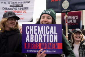 Young woman holds "Chemical Abortion Harms Women" sign outside SCOTUS during Pro-Life rally