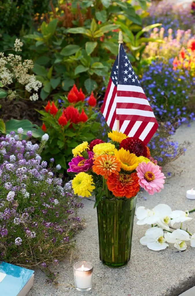 A vase of flowers with an American Flag placed at the UM Oval memorial site for Charlie Kirk