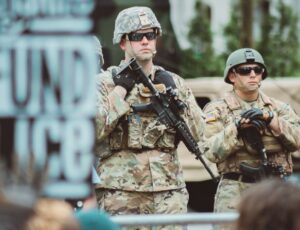 man in brown and black camouflage uniform holding rifle