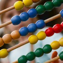 Photo by ClickerHappy Close-up of colorful wooden abacus with a child learning math in the background, focusing on education and early childhood development.