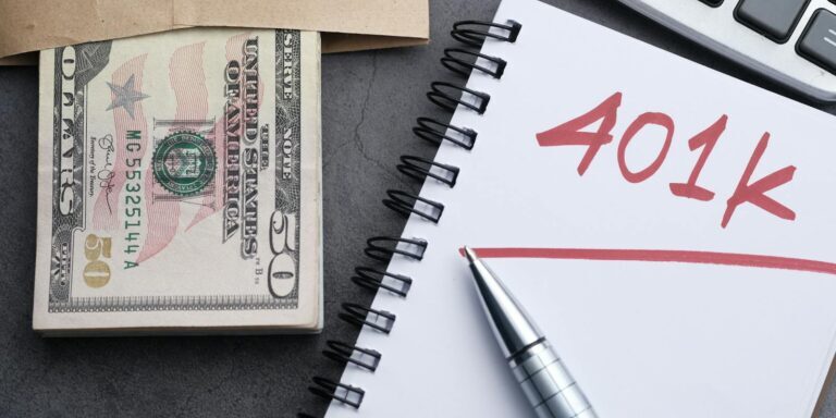A desk setup with a notebook labeled '401k', a pen, cash, and a calculator representing financial planning.
