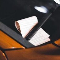 Close-up of a parking ticket on a car windshield at night, highlighting urban parking issues.