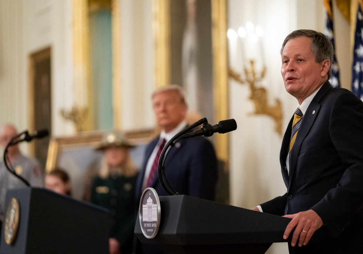 President Donald J. Trump listens as Senator Steve Daines, R-Mont., delivers remarks