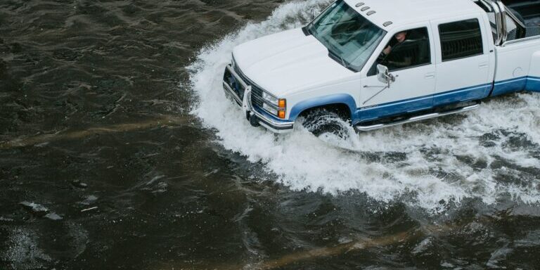 White crew cab truck navigating flood.