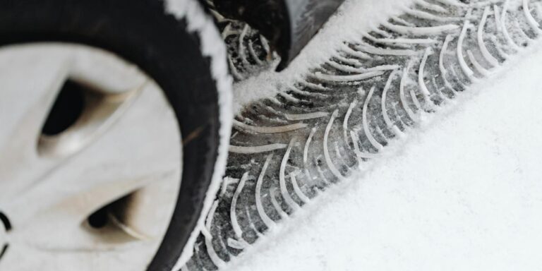 A detailed view of vehicle tire tracks on a snow-covered road during winter.