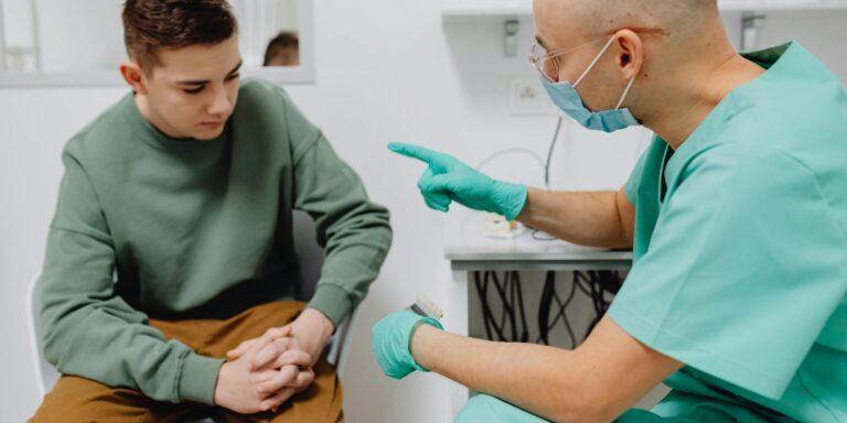 A teenager consults a doctor in a clinic, discussing health concerns.