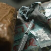 Photo by MART PRODUCTION A dramatic scene depicting drugs and syringes on a dark surface, highlighting substance abuse risks.