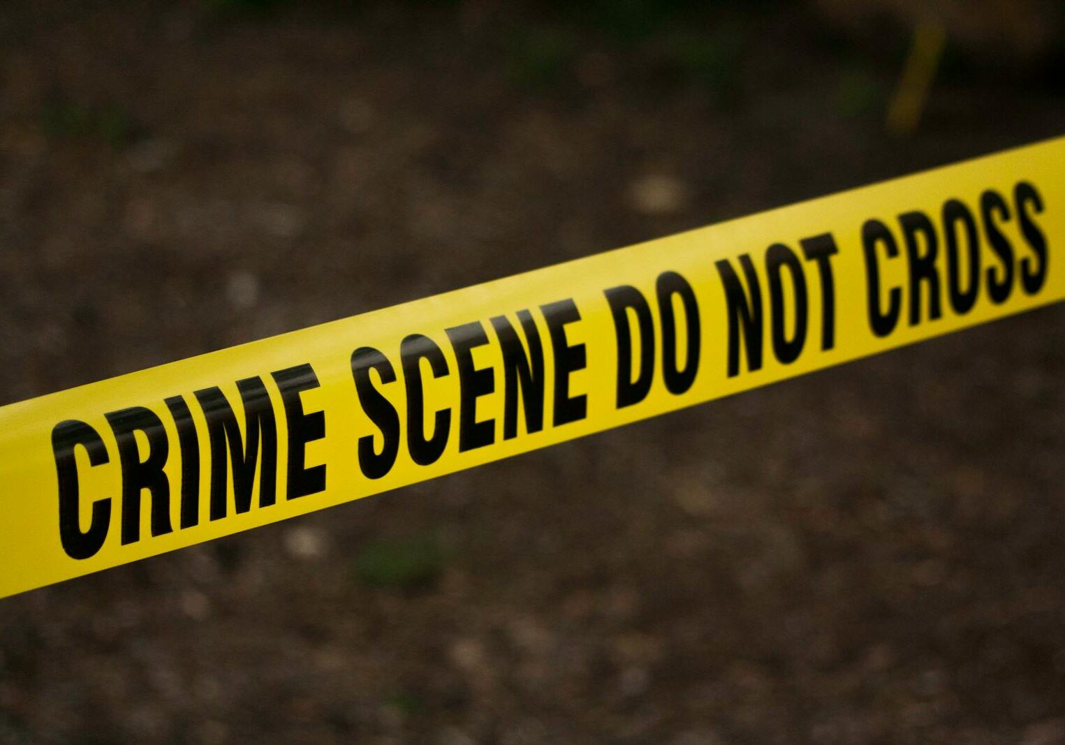 Photo by kat wilcox Close-up of crime scene tape with 'Do Not Cross' text, outdoors setting.