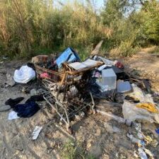 A shopping cart filled with trash surrounded by more trash near the Clark Fork River waterfront A shopping cart filled with trash surrounded by more trash near the Clark Fork River waterfront