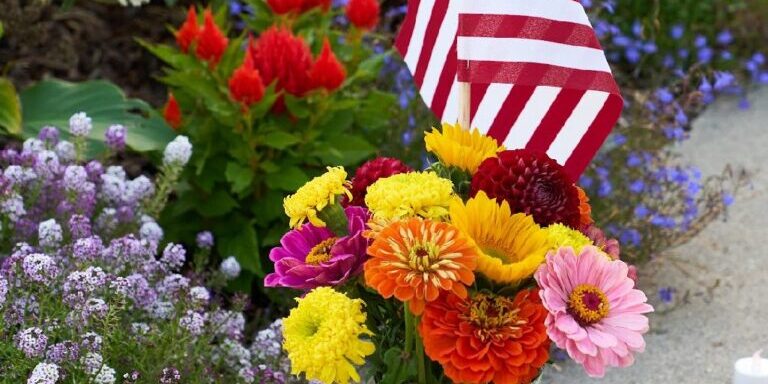 A vase of flowers with an American Flag placed at the UM Oval memorial site for Charlie Kirk
