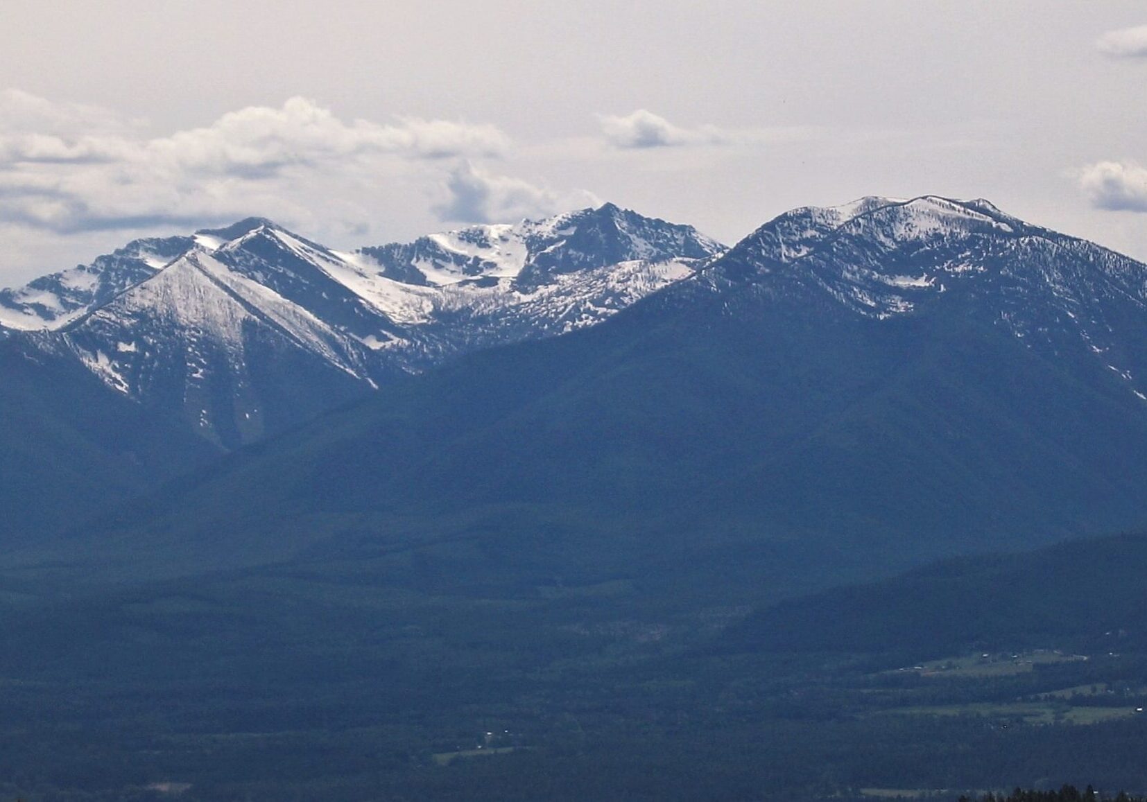 Snow-Capped Mountain Range Under Cloudy Sky