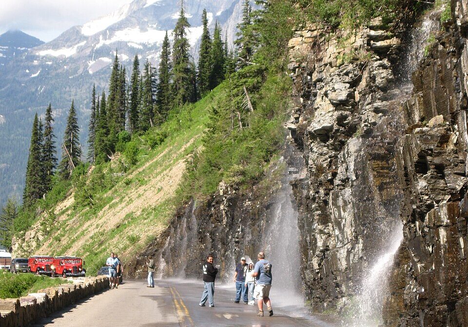 Alpine Cliff Waterfall Sprays Across Mountain Road