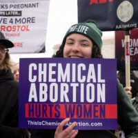 Young woman holds "Chemical Abortion Harms Women" sign outside SCOTUS during Pro-Life rally Young woman holds "Chemical Abortion Harms Women" sign outside SCOTUS during Pro-Life rally