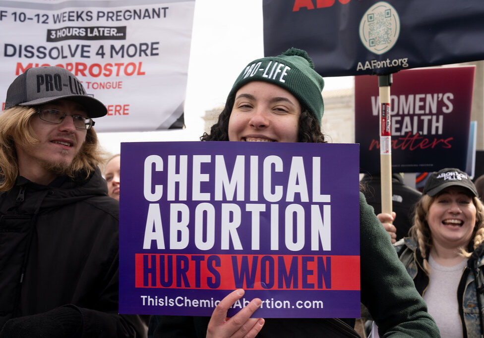 Young woman holds "Chemical Abortion Harms Women" sign outside SCOTUS during Pro-Life rally