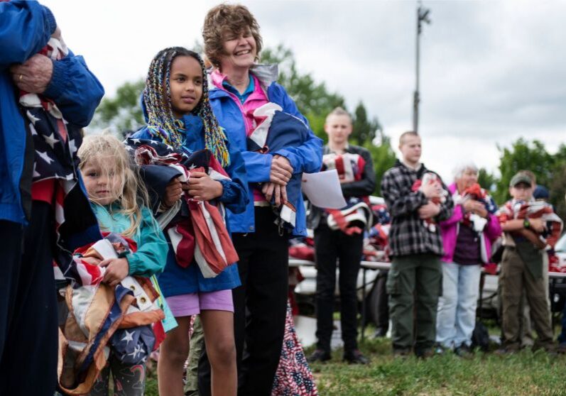 Nora Kappelman, 5, left, and sister Sophia Kappelman, 9, wait in line to dispose of unserviceable flags during an American Legion Post 27 ceremony on Flag Day in Missoula, MT 2020. Photo by Tommy Martino/The American Legion