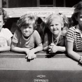 Four children look on from the back window of a Chevrolet station wagon. Coastwatch Magazine. 1979. Four children look on from the back window of a Chevrolet station wagon. Coastwatch Magazine. 1979.