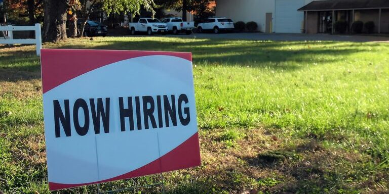 a now hiring sign in front of a building