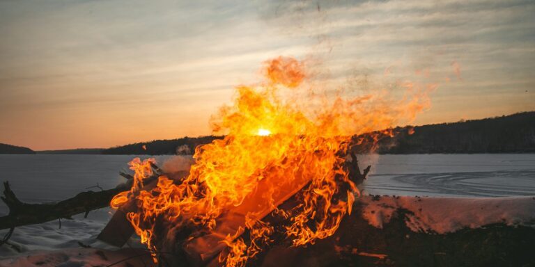 a fire burning in the middle of a snow covered field