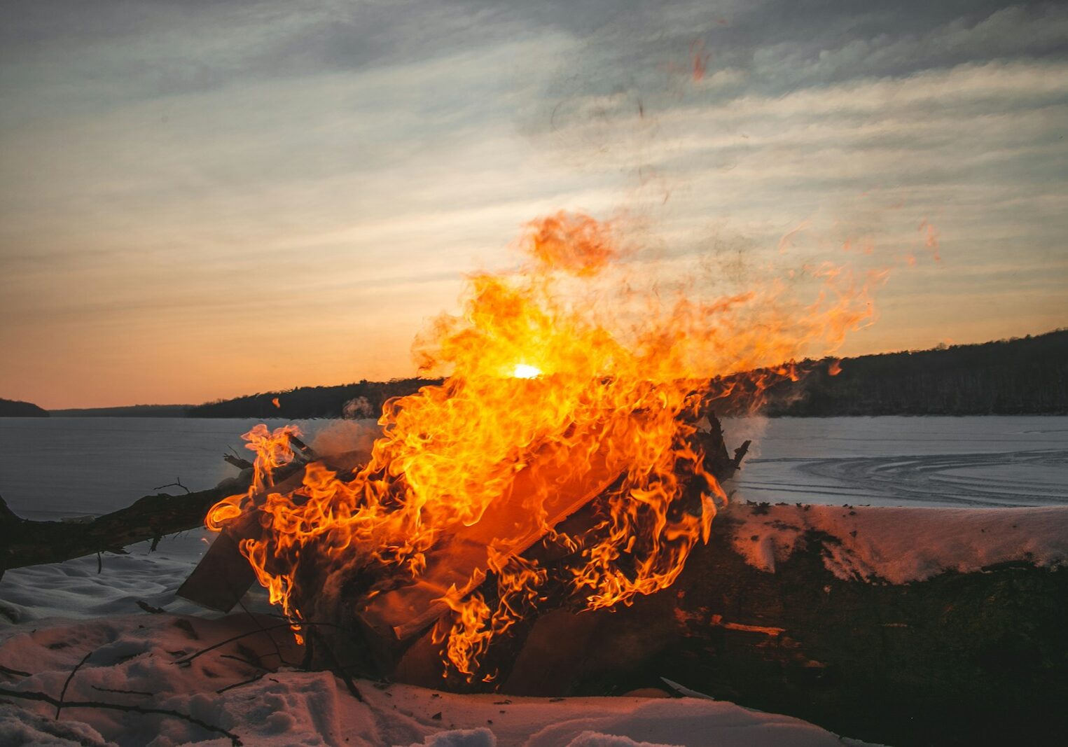 a fire burning in the middle of a snow covered field