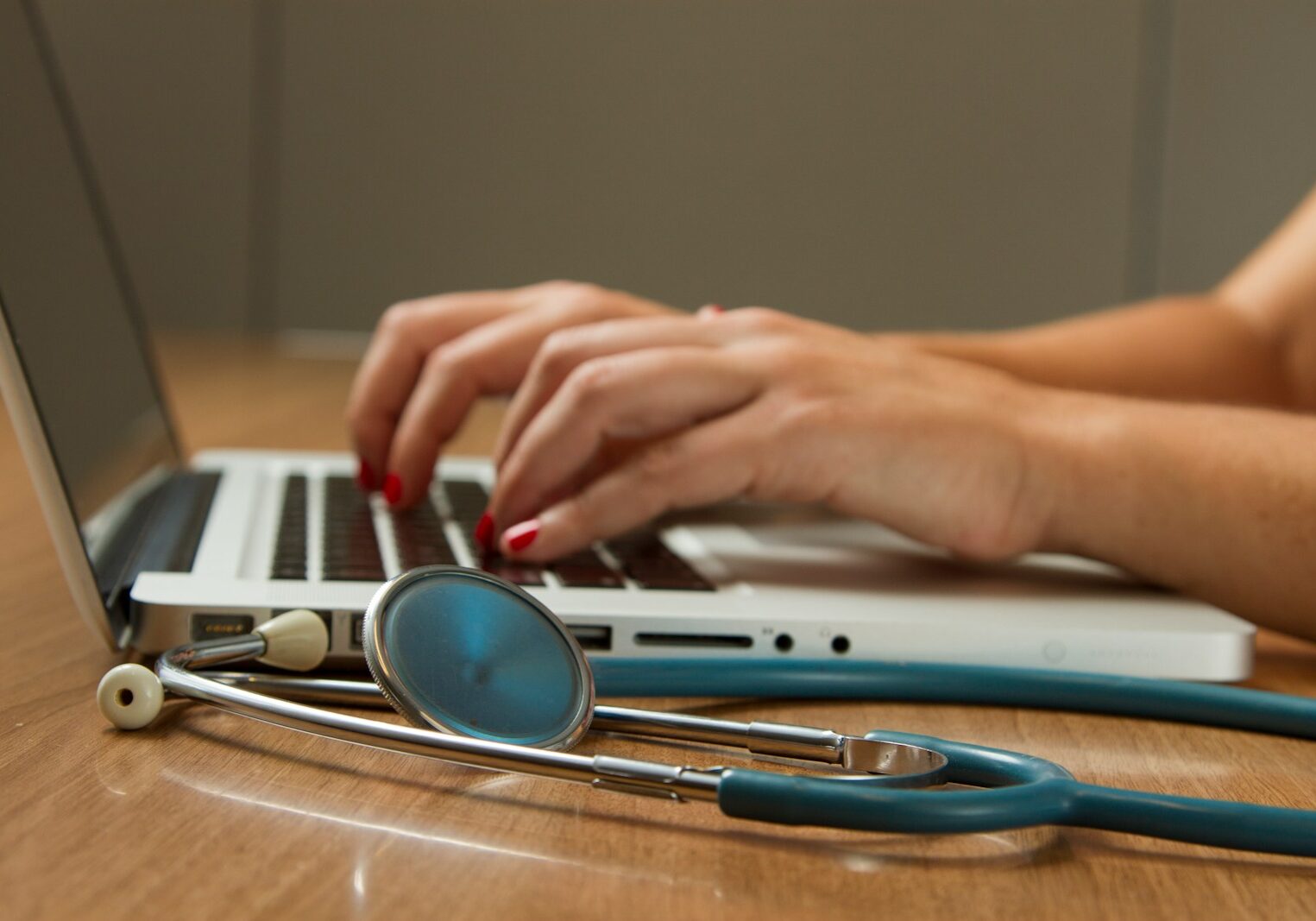 Photo by National Cancer Institute person sitting while using laptop computer and green stethoscope near