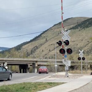 Rural Railroad Crossing with Traffic and Mountain Backdrop