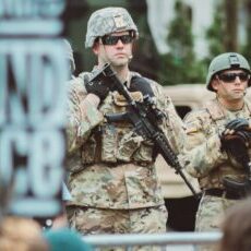 man in brown and black camouflage uniform holding rifle