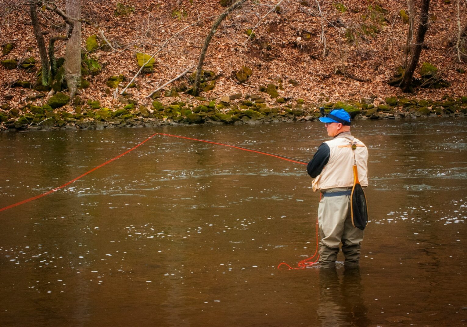 Photo by Paul Wolke woman in brown jacket and brown skirt fishing on river during daytime