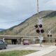 Rural Railroad Crossing with Traffic and Mountain Backdrop